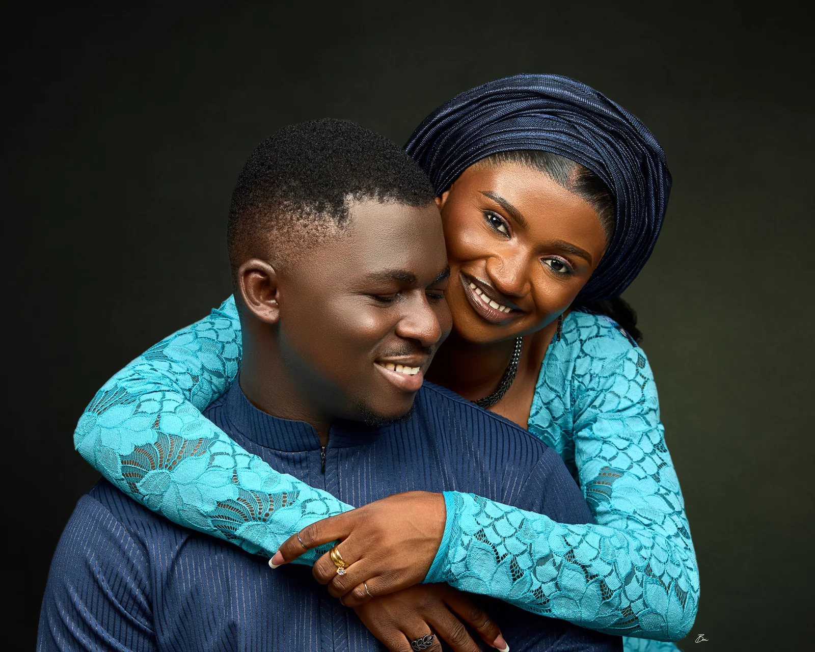 The couple smiling together in blue traditional outfits